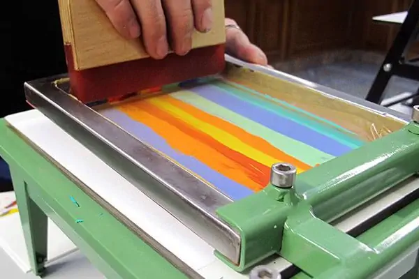 عکس دستگاه چاپ سیلک دستی در حین کار با چند رنگ مختلف