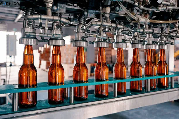 خط تولید نوشابه در حال کار با بطری‌ها و دستگاه‌های صنعتی پیشرفته، نشان‌دهنده فرآیند تولید و بسته‌بندی نوشابه.