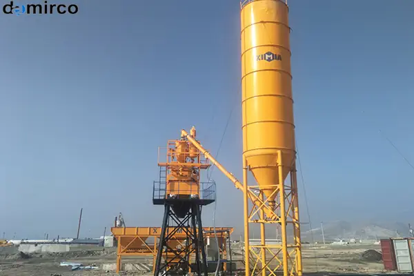 سیلو سیمان در کنار کارخانه بتن آماده در حال عملیات، نشان‌دهنده اهمیت نگهداری و تأمین سیمان برای تولید بتن با کیفیت.