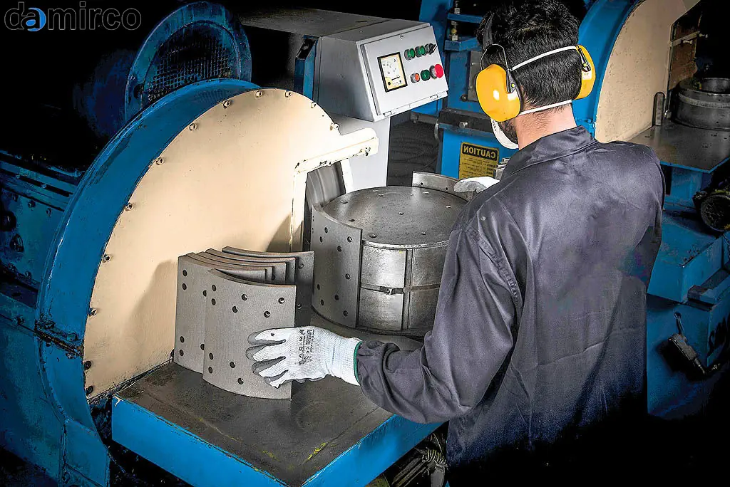 تصویری از یک خط تولید مدرن لنت ترمز با ماشین‌آلات خودکار و اپراتورهای متخصص که در حال نظارت بر فرآیند تولید هستند.