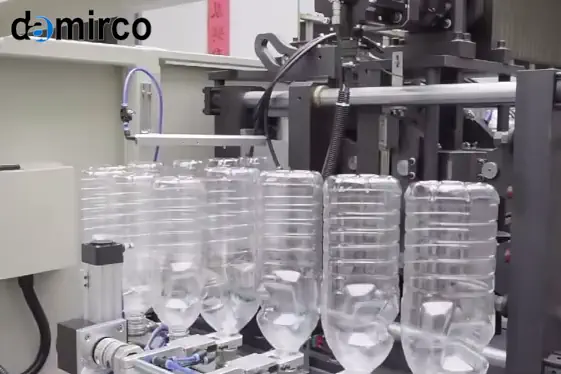 یک دستگاه بادکن پت اتوماتیک در حال تولید بطری‌های شفاف پلاستیکی در یک خط تولید صنعتی