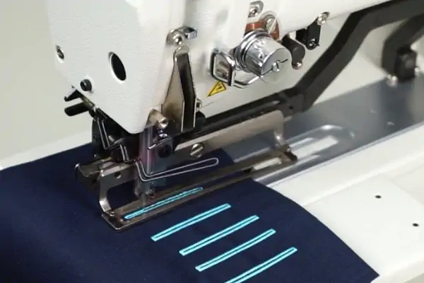 عکس دوخت جادکمه آبی روی پارچه سورمه ای با چرخ جادکمه دوز سفید رنگ