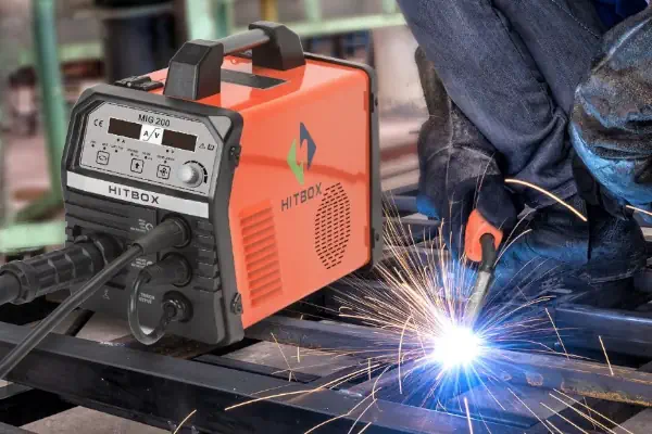 دستگاه جوش میگ مگ در کنار جوشکاری که لوله را جوش می دهد.