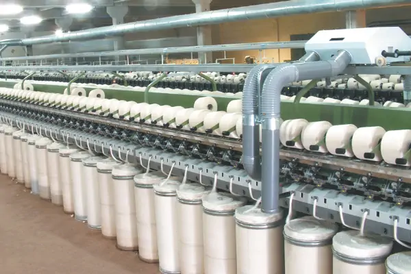 عکس نخ های سفید رنگ به صورت ردیف به همراه دستگاه ریسندگی