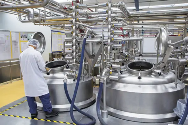 عکس انسان با روپوش سفید و کلاه یک بار مصرف در خط تولید شیر