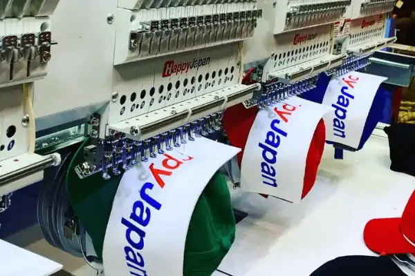 عکس دستگاه گلدوزی کلمه خارجی آبی و قرمز روی پارچه سفیدسفید رنگ ب